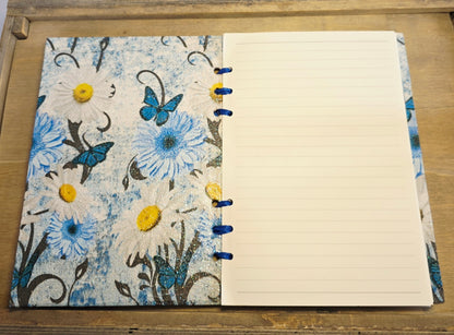 Notebook with floral cover on a wooden surface. white lined pages