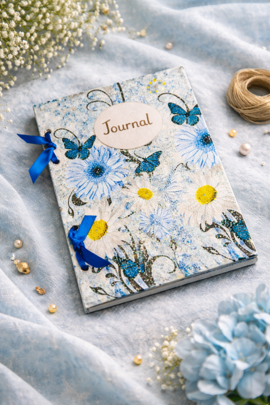 Decorative wooden journal with floral butterfly design on a soft fabric background