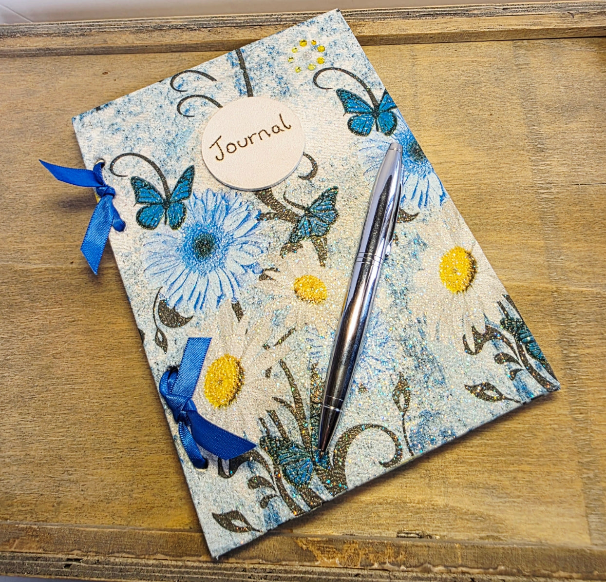 Decorative journal with floral and butterfly design on a wooden surface