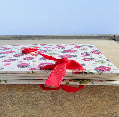 Ladybird themed notebook with a red ribbon on a wooden surface