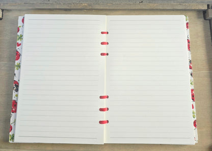 Open notebook with lined pages on a wooden surface. Bound with red ribbon