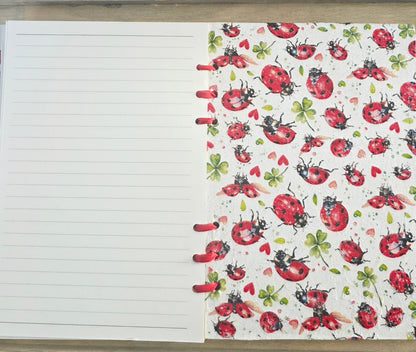 Notebook with a colorful ladybug pattern on the cover. Bound with red ribbon