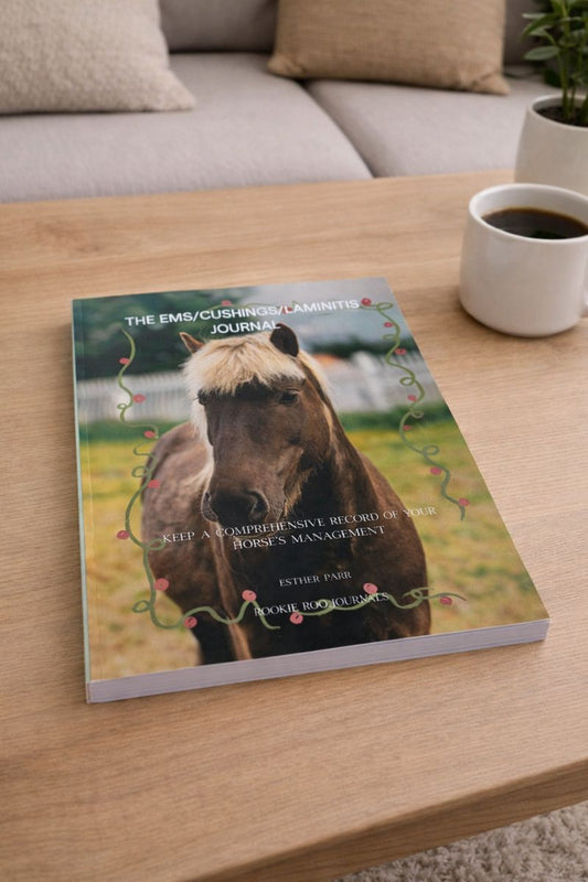 Paperback journal titled 'The Ems/Cushing's Laminitis Journal' on a wooden table with a cup of coffee.