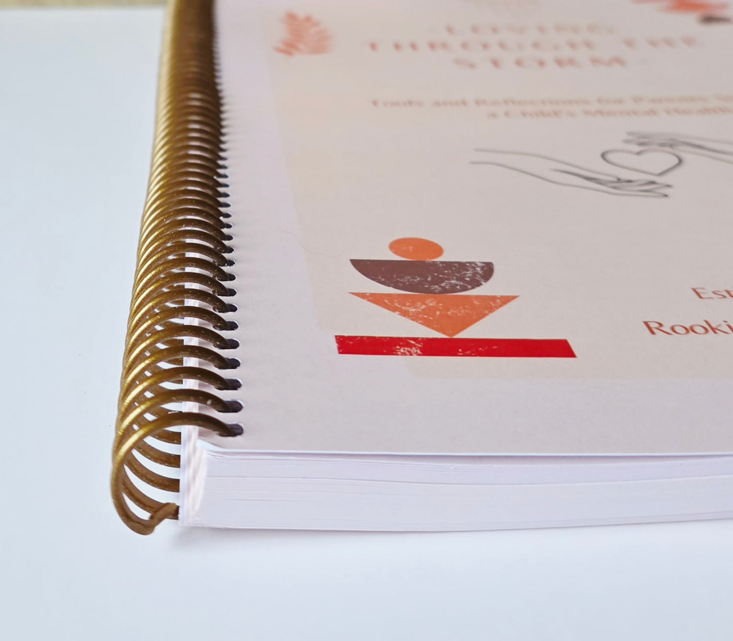 Close-up of a spiral-bound book with a logo on a white background