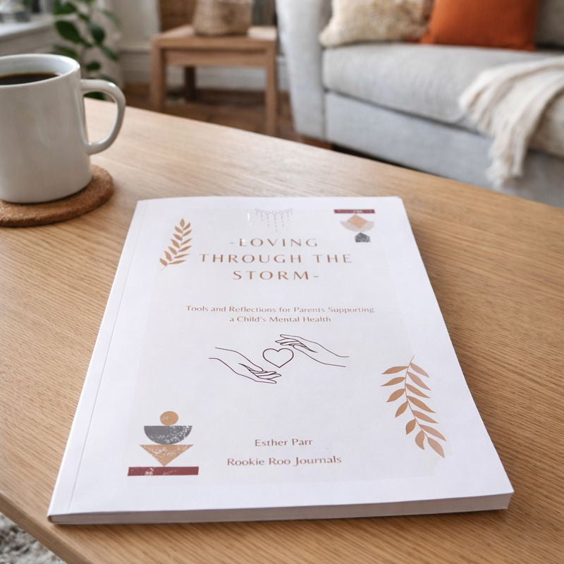 Book titled 'Loving Through the Storm' on a table with a cup of coffee in a cozy living room.