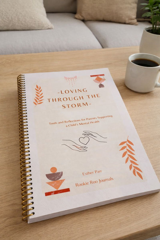 Book titled 'Loving Through the Storm' on a wooden table with a cup of coffee and a plant in the background.