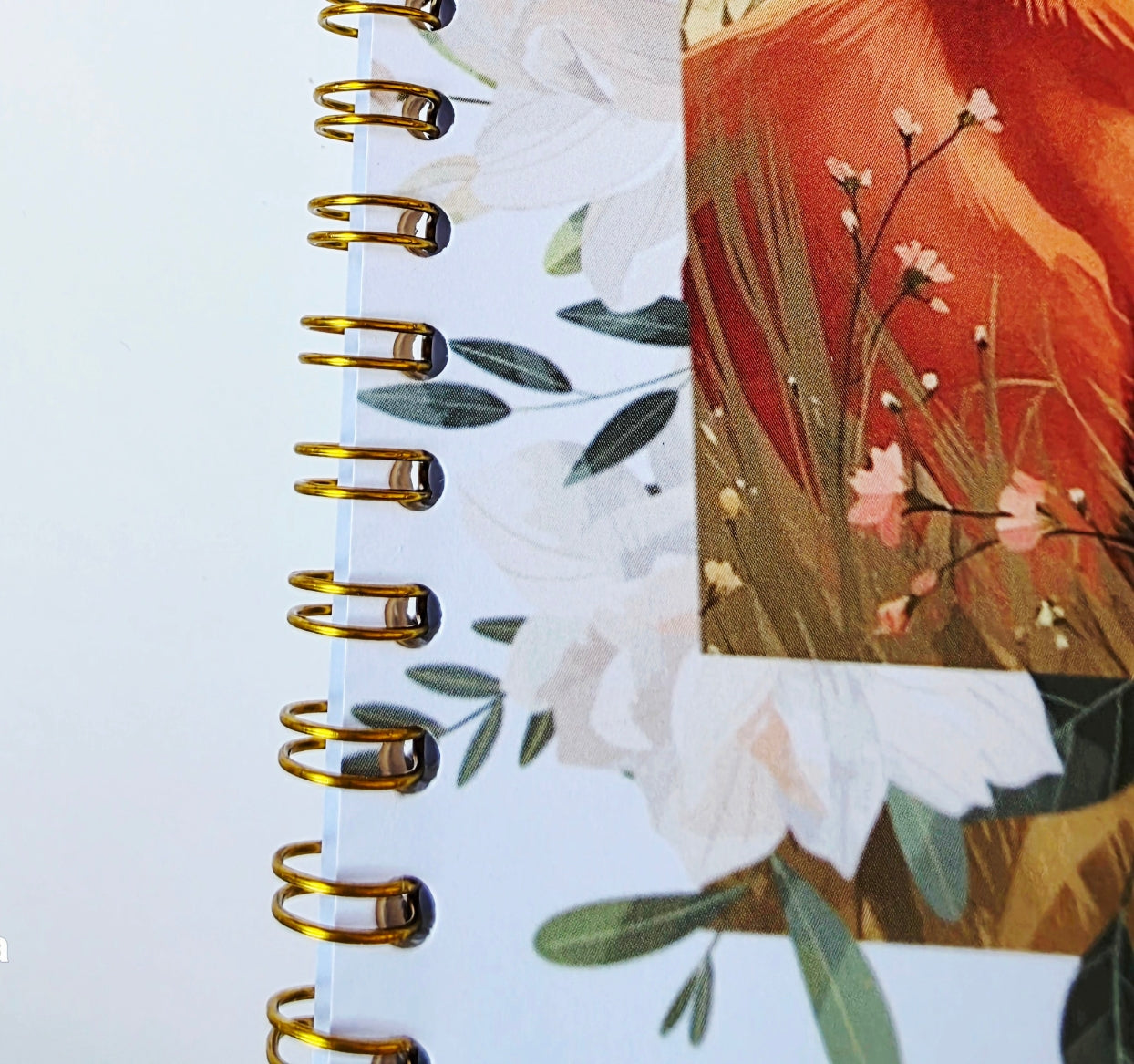 gold Spiral-bound notebook with floral design on a white background