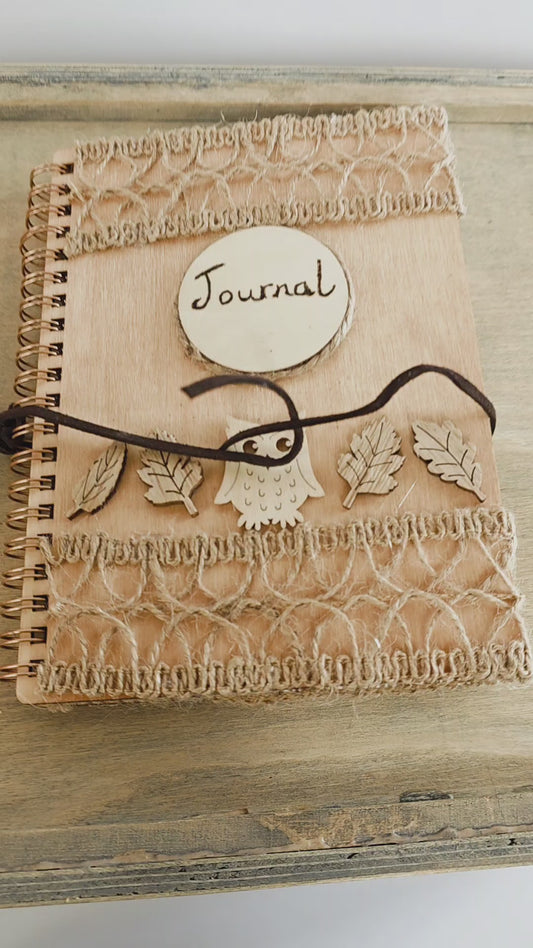 Video of a Wooden journal with decorative woodland elements and burlap design top and bottom. Dark brown faux suede tie. Round journal sign on the front. Spiral bound