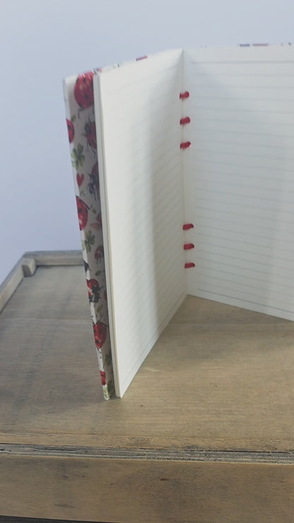 video of a ladybird themed notebook, showing inside lined pages and bound with red ribbon