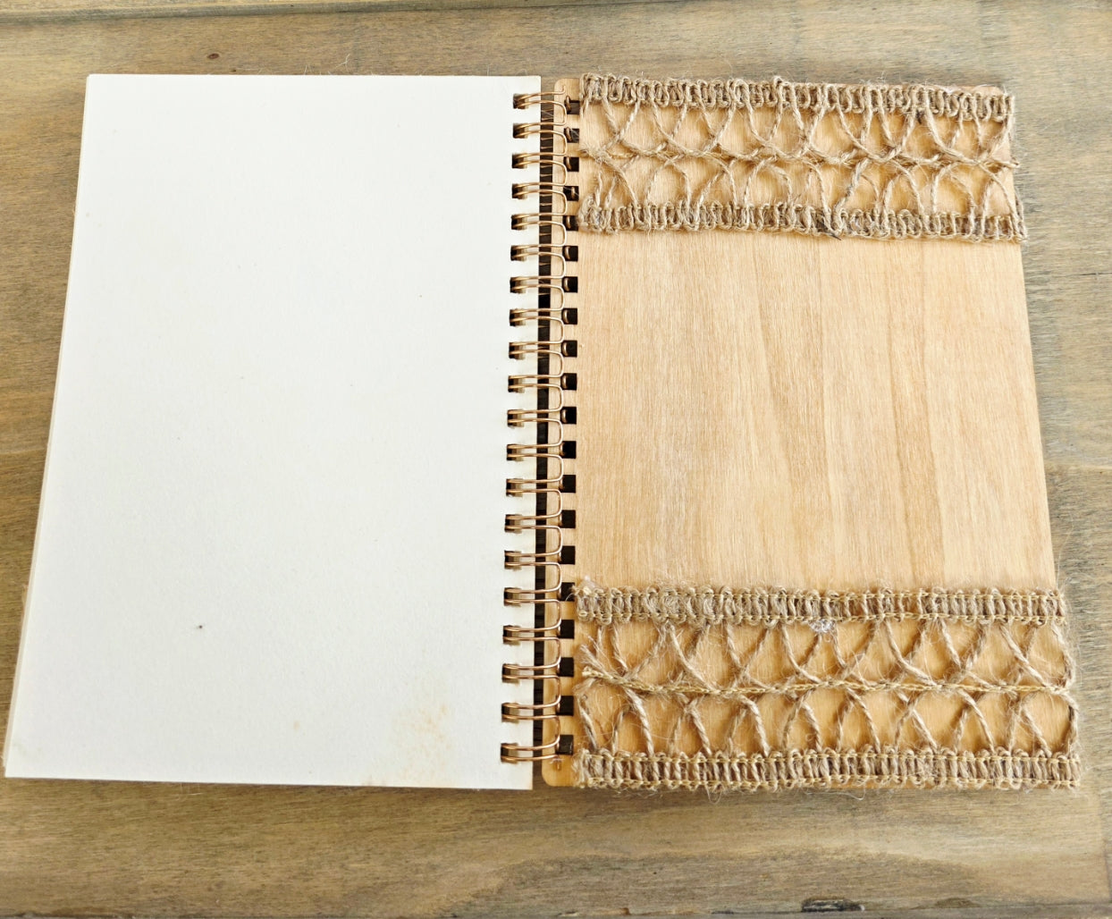 Open wooden notebook with a decorative burlap on the back inside cover. Spiral bound with plain pages