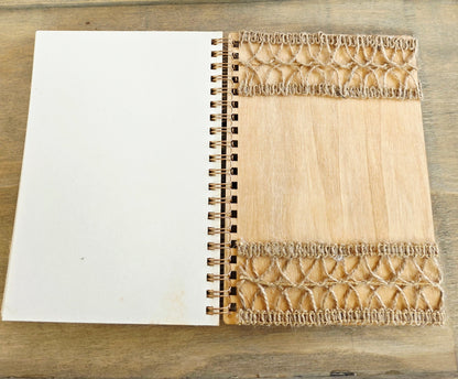 Open wooden notebook with a decorative burlap on the back inside cover. Spiral bound with plain pages