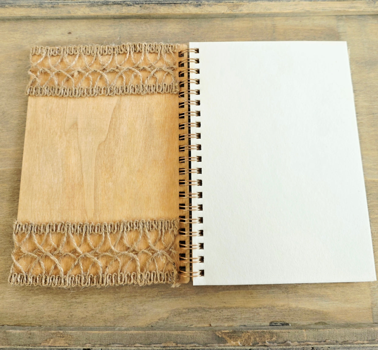 Open wooden notebook with a decorative burlap inside cover. Spiral bound with plain pages