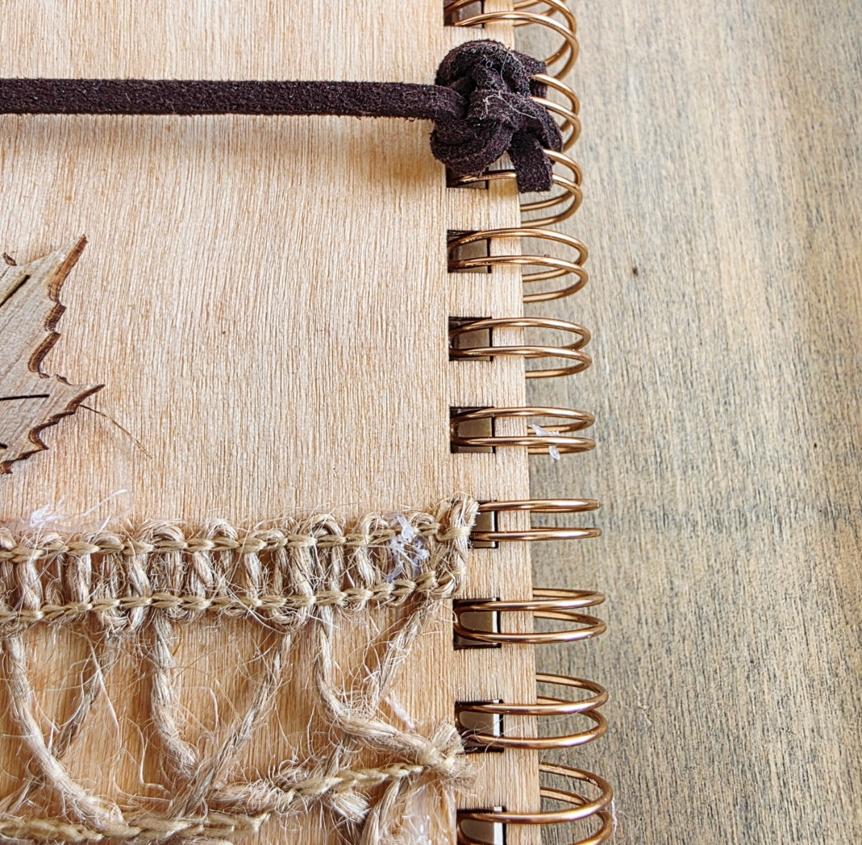 Wooden journal with decorative woodland elements and burlap design at the bottom. Dark brown faux suede tie. Round journal sign on the front. Spiral bound